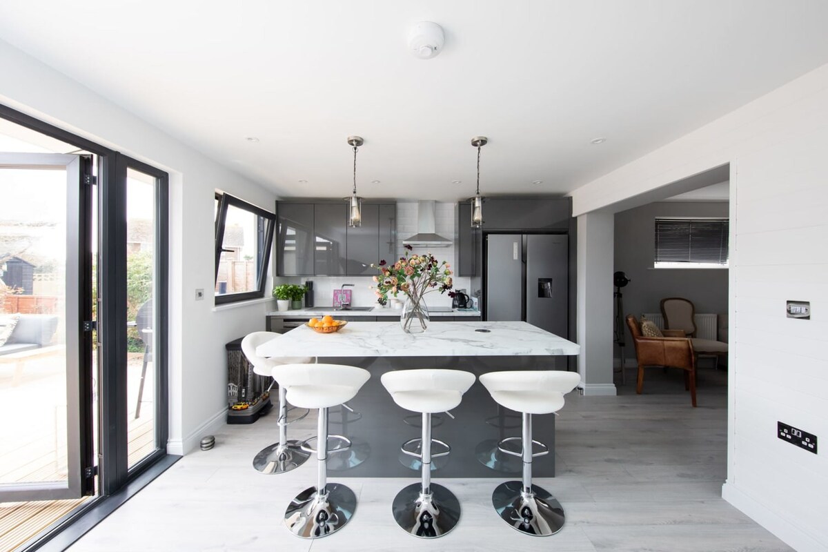Dark cabinetary with spacious white countertops and a large kitchen island, provide plenty of working space as well as breakfast bar.