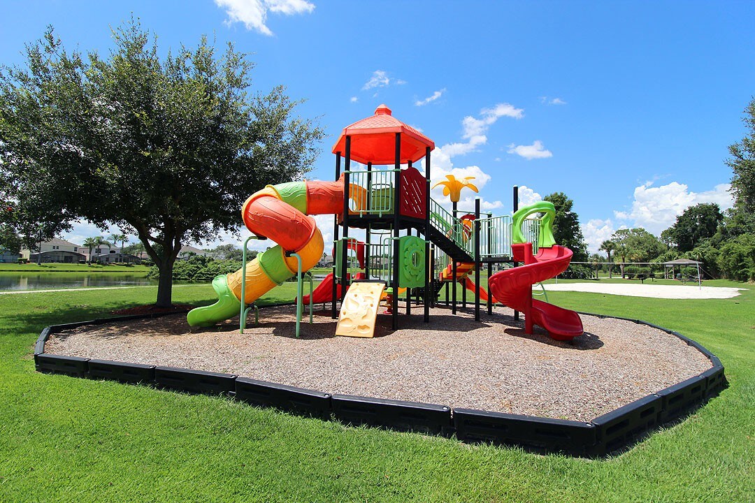 Colorful playground w/ slides and climbing features in an open park setting.