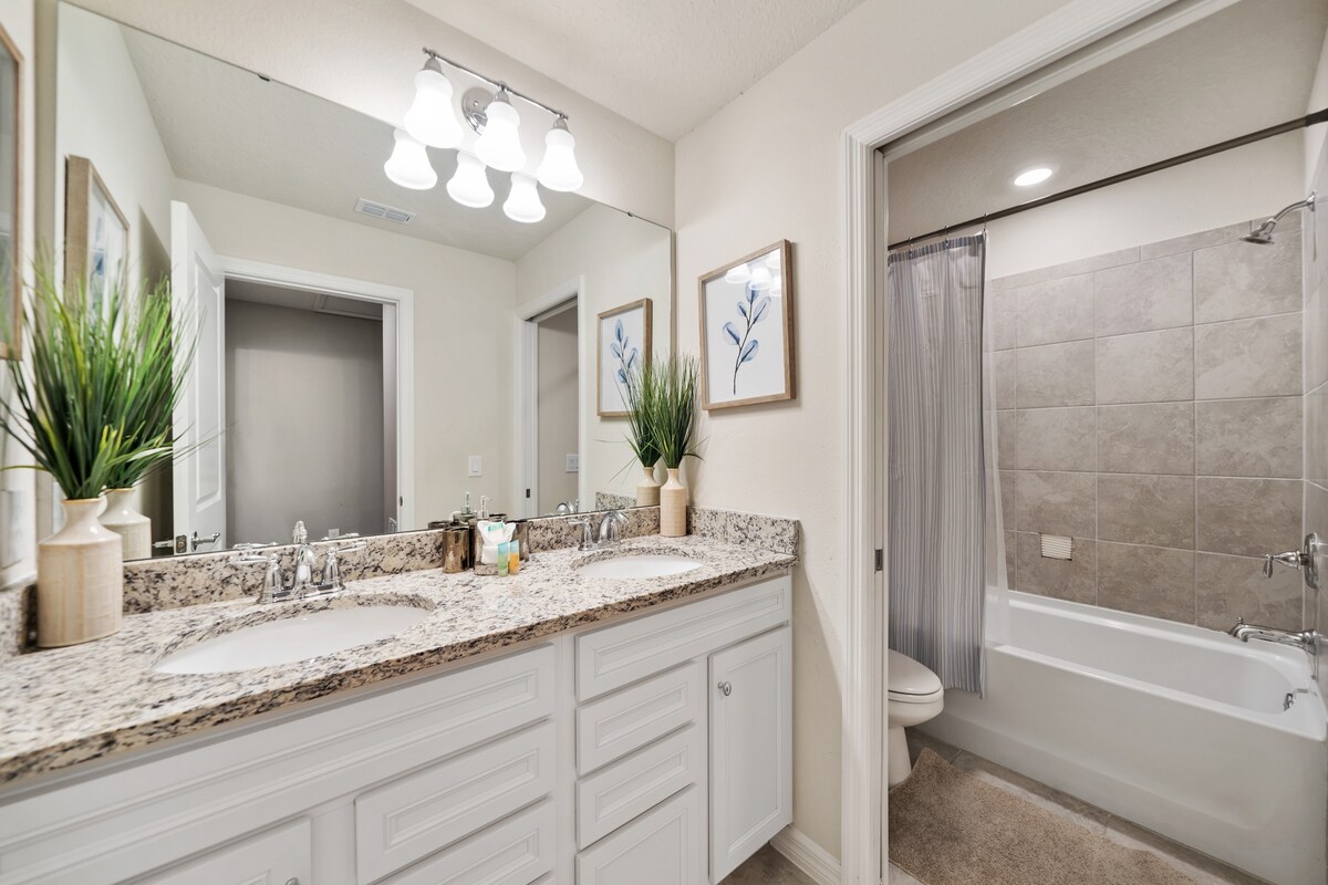 Jack-and-Jill bathroom features a shared layout w/ clean, bright finishes.