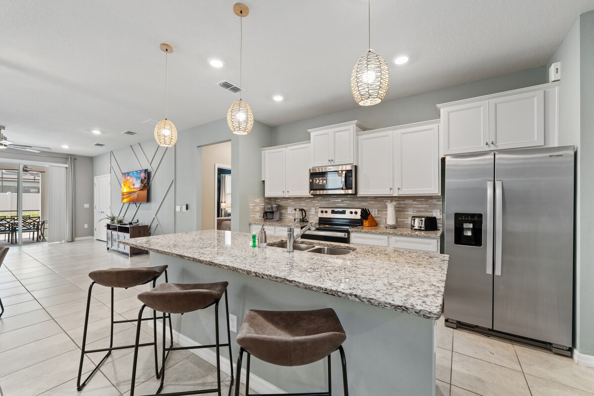 Kitchen island w/ stainless appliances anchors the open cooking space.