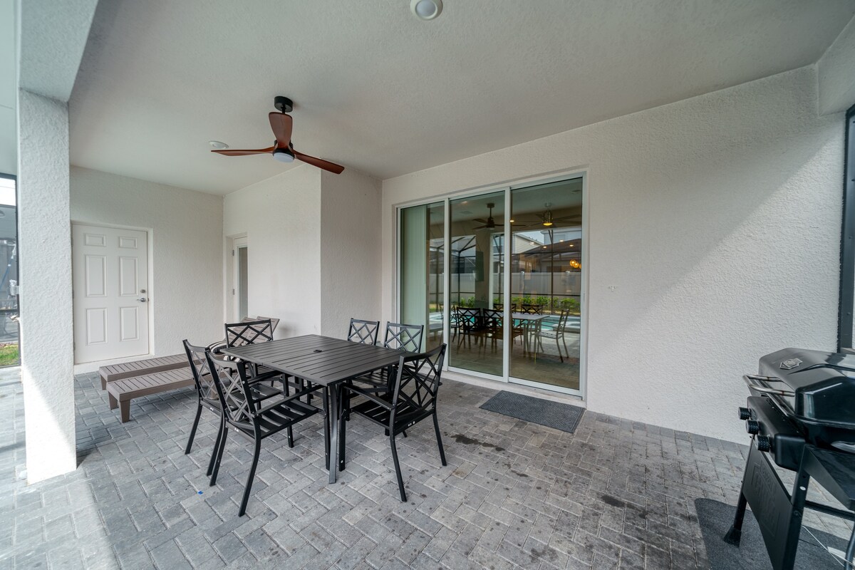 Covered patio w/ outdoor dining, ceiling fan, and grill setup for relaxed meals outside.