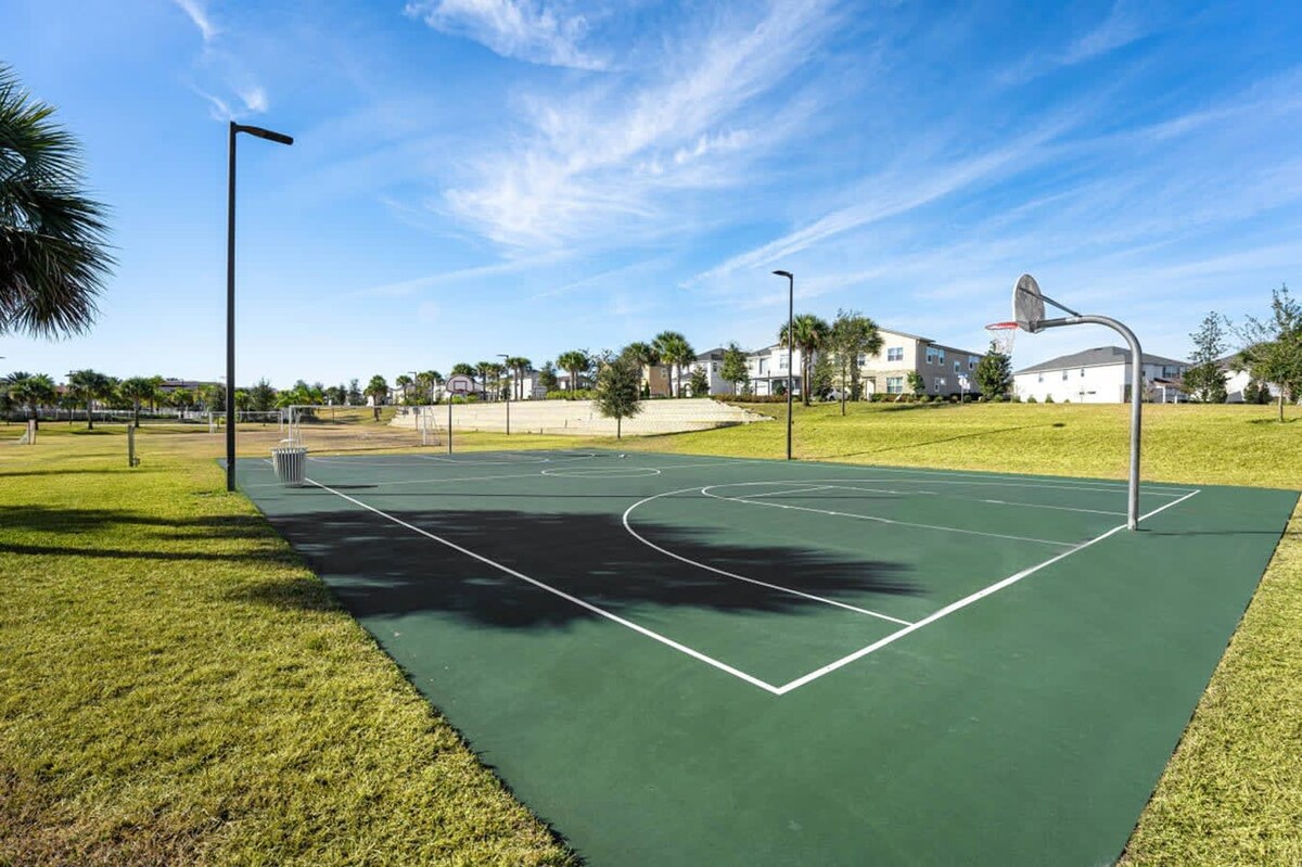 Modern Tennis Court Surrounded By Open Fields And Blue Skies
