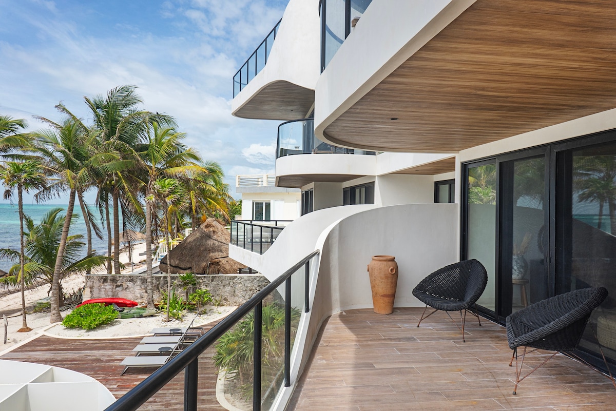 Apartment balcony with outdoor chairs and ocean views.