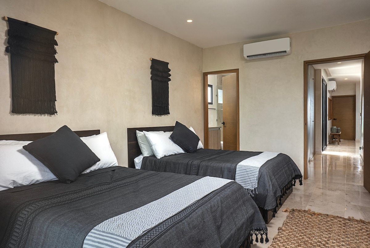 Second bedroom with two double beds and a private bathroom.