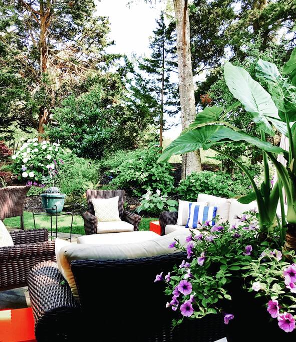 Furnished corner of the private deck with wicker seating amid potted plants and flowers.