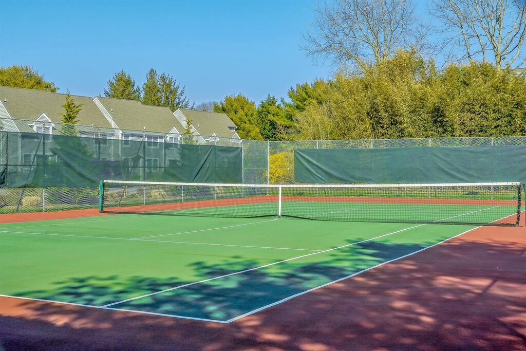 Community tennis court with a green playing surface and shaded fencing.