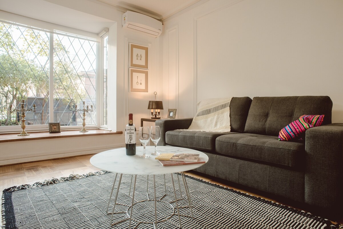 Relax in this stylish living room with a cozy sofa, natural light, and a perfect spot for a glass of wine.