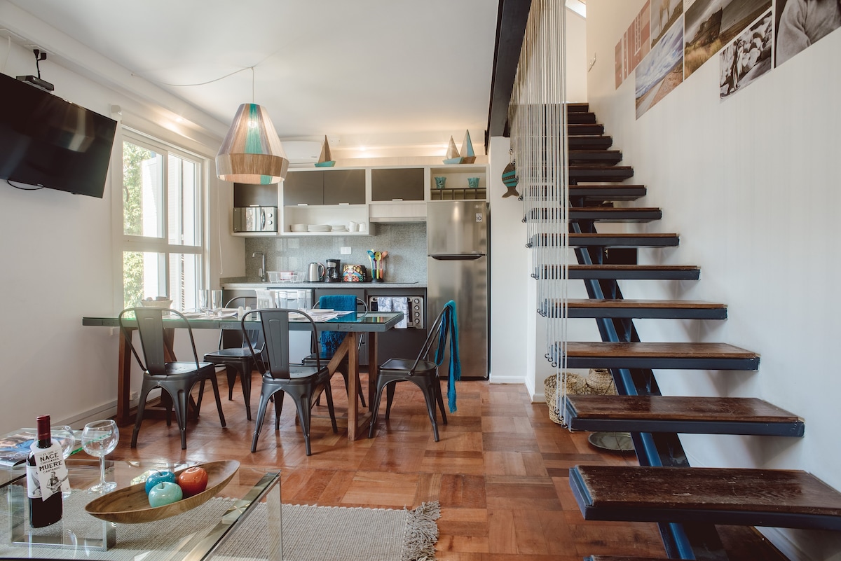 Chic kitchen and dining space with modern amenities and a unique floating staircase, perfect for stylish gatherings.