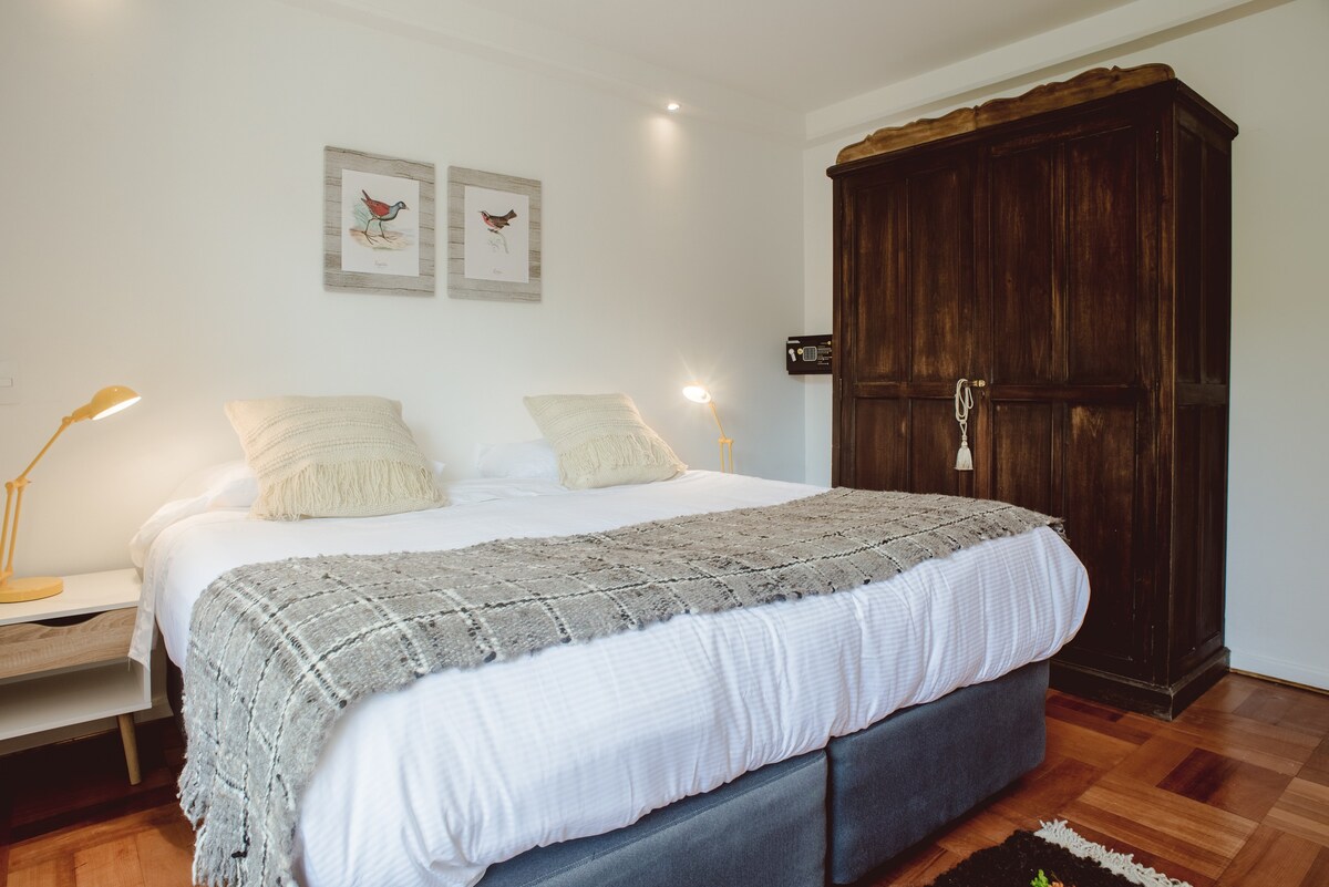 Cozy bedroom with a plush bed, charming bird art, and rustic wooden accents for a serene retreat.