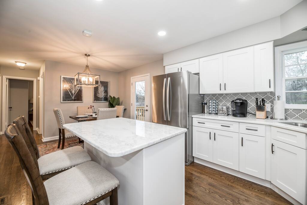 Gather around the island while dinner comes together — this fully equipped white kitchen makes cooking for twelve feel effortless.