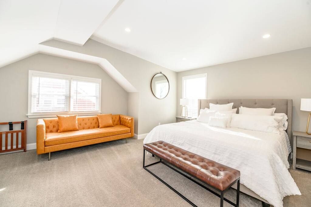 Stretch out on your own leather sofa before bed — a king bed under the sloped ceiling, a bench at the foot for stacking your bags.