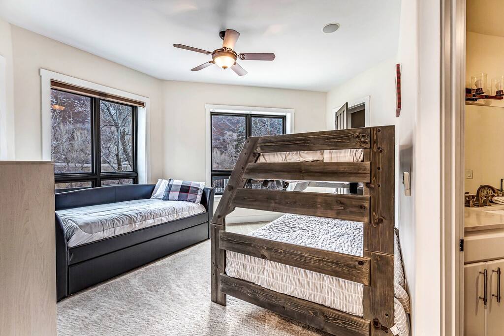 Upper-level bedroom w/ a bed, ceiling fan, and rustic railing overlooking the space below.