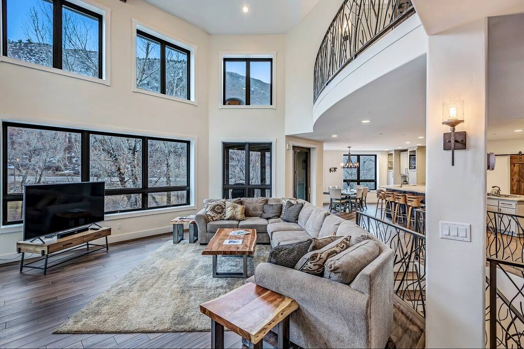 Bright living area w/ cozy seating and large windows framing the outdoors.