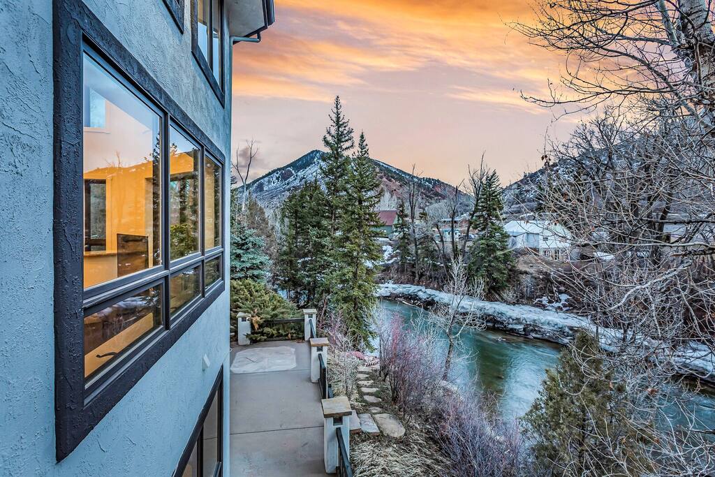 Scenic balcony view overlooking trees and nearby homes at sunset.