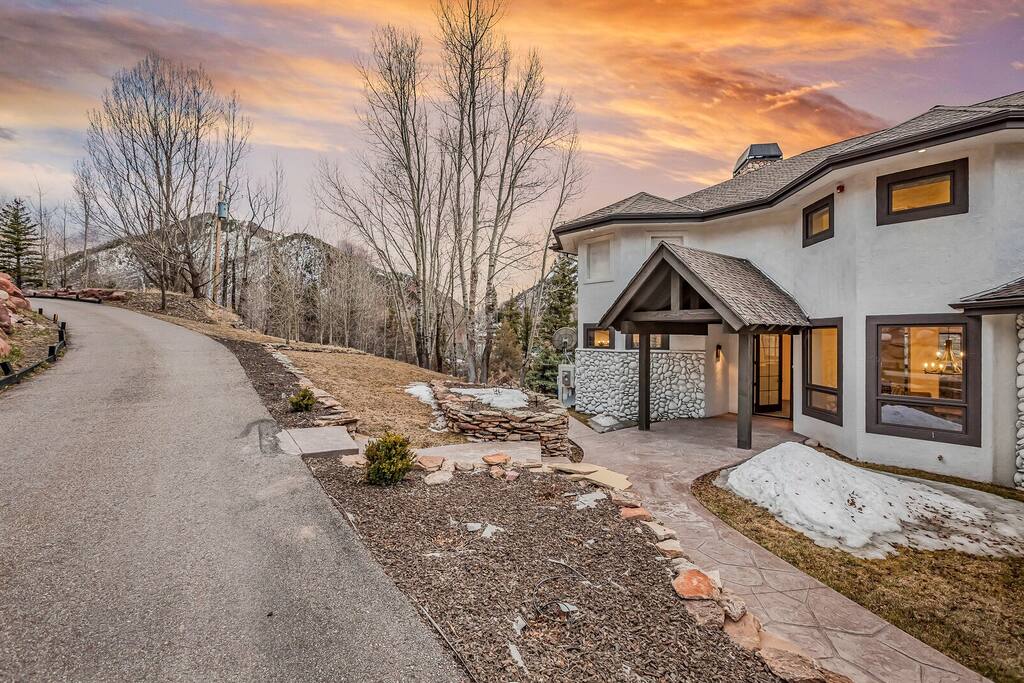Curved driveway leading to the home, framed by trees and soft evening light.