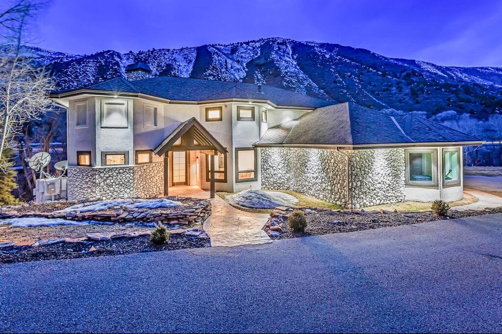 Twilight exterior glowing warmly against a dramatic mountain backdrop.