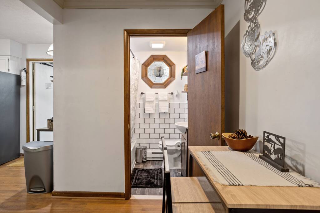 Hallway View into Stylish Bathroom
This warm hallway leads into a beautifully updated bathroom featuring white subway tiles, matte black accents, and a unique octagonal window that brings in natural light.