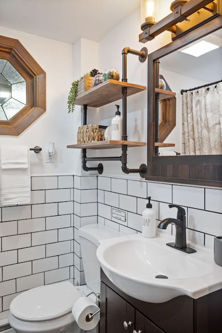 Sink and Mirror Detail with Open Shelving
Open pipe shelving adds a rustic-industrial charm, paired with matte black hardware and warm wood textures for a cozy, polished finish.