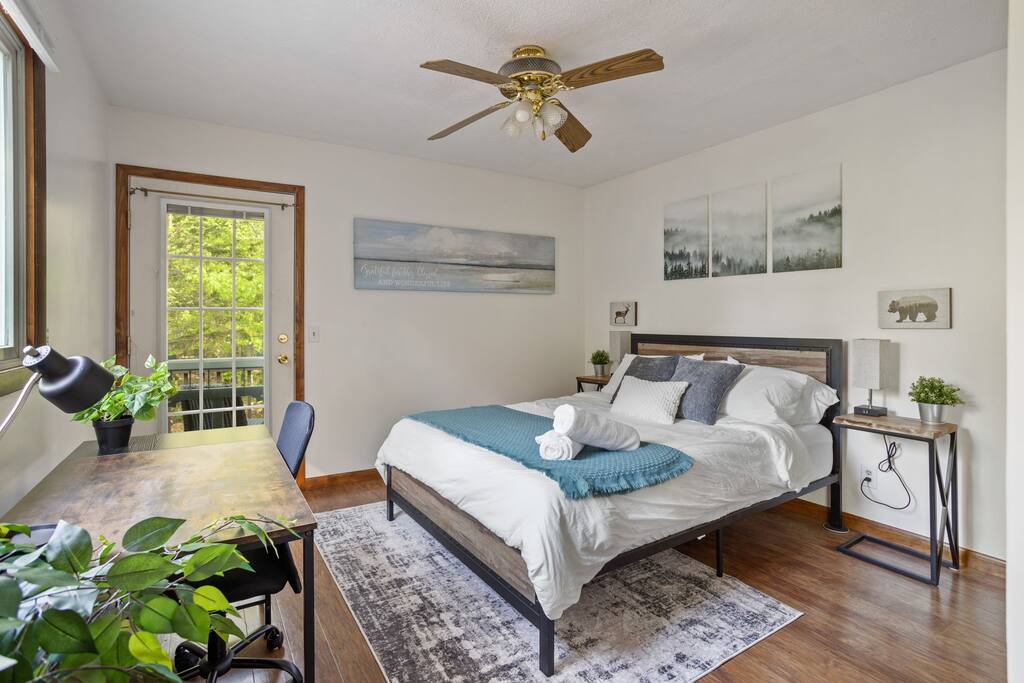 Main View
Bright and airy with calming tones, this spacious bedroom features a queen bed, ceiling fan, and nature views through every window.
