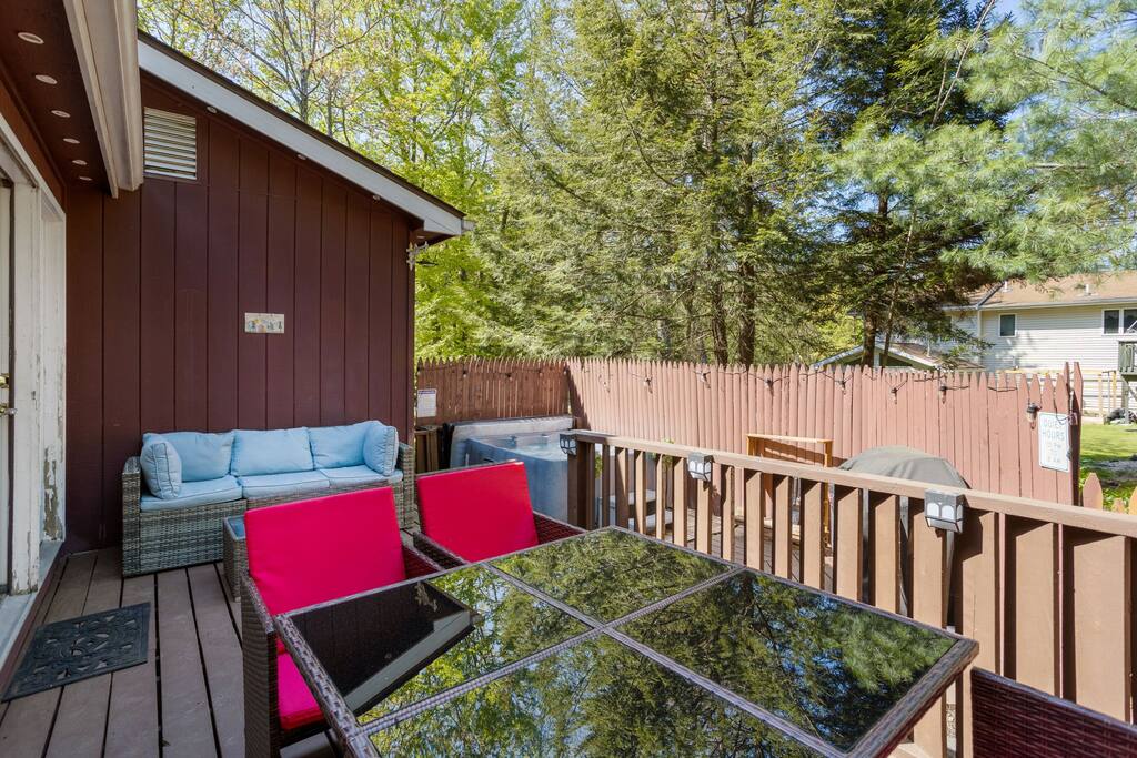A fun and vibrant setup featuring a glass-top table and bright red cushioned seating, perfect for grilling, dining, and lounging in the sun.