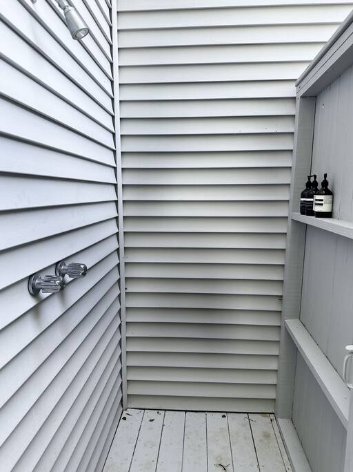 Outdoor shower stall with a wood-slat enclosure and dual shower heads.